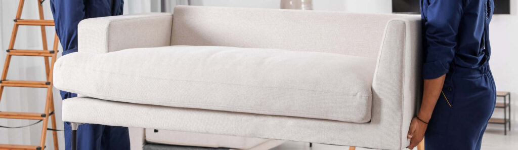Delivery professionals carefully carrying a sofa into a home representing same-day furniture delivery service by My Home Delivery