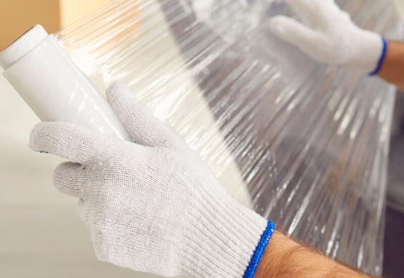 Delivery professional carefully moving wrapped furniture into a home representing white glove delivery service by My Home Delivery